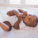 A playful baby lying in a crib holding their feet
