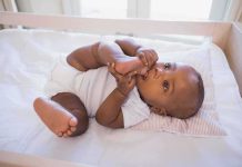 A playful baby lying in a crib holding their feet