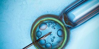 Close up of a needle and vial with liquid droplets on a blue background