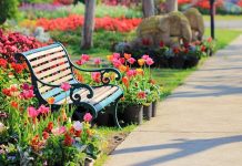 A decorative garden bench surrounded by vibrant flowers in a park