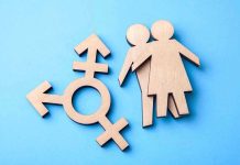 Wooden transgender symbol and couple figures on blue background.