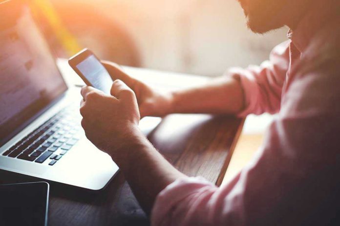 Person using a smartphone and laptop at desk