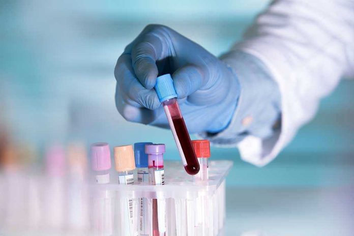 441264445 Gloved hand holding a blood sample test tube.