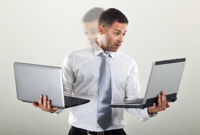 532697098 Man holding two laptops and looking surprised.