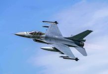 Jet fighter flying through clear blue sky.