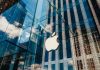 Apple store with glass facade and city reflections.