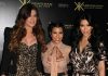 Three Kardashian sisters posing together at a fashion event