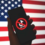 Trump Seeks TikTok Ban Reprieve From SCOTUS Over Security Worries Phone displaying TikTok ban symbol in front of flag