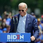 Biden Honors Key Figures In January 6 Probe And Civil Rights Movement Man speaking at outdoor campaign event with sunglasses