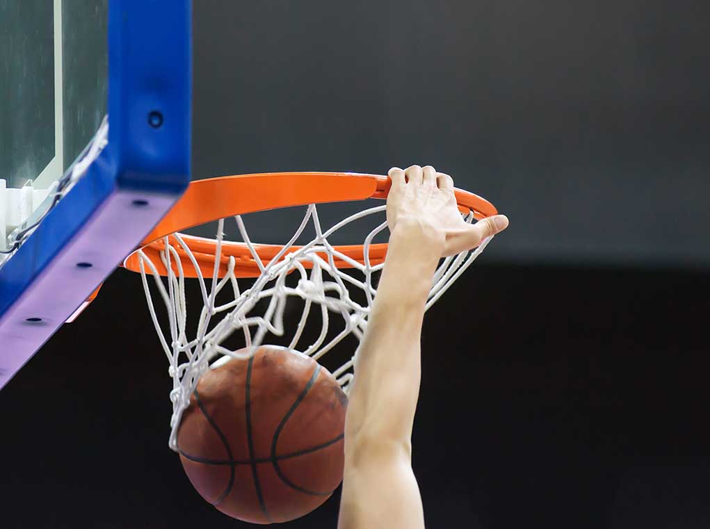 1448640140 featured image Hand dunking a basketball through a hoop.