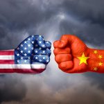 Two fists with US and China flags facing