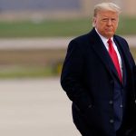 Political Tensions and Safety Issues Arise After D.C. Air Disaster Man in coat holding smartphone, outdoors.