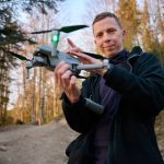 Person holding a drone in a forest.