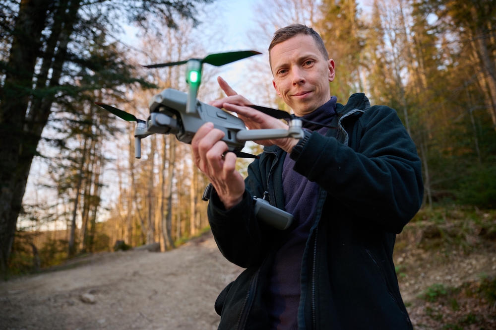 Person holding a drone in a forest.
