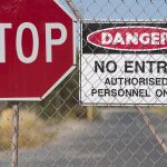 "Stop and Danger signs on a chain-link fence."