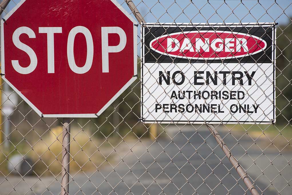 "Stop and Danger signs on a chain-link fence."