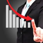 Businessman pointing at declining bar graph.