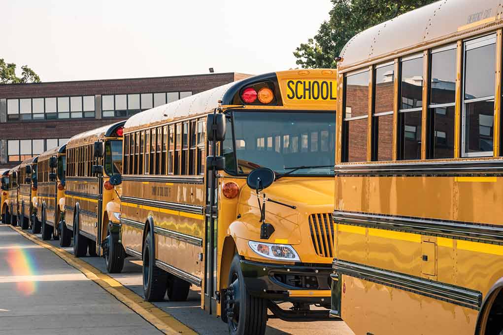 1167553465 featured image School buses lined up in front of building.