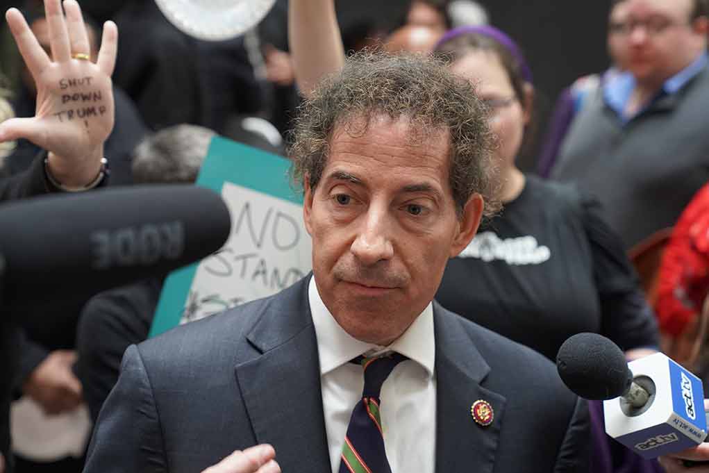 1303300717 featured image Man in suit surrounded by microphones and protesters