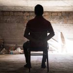 Hamas Halts Hostage Talks: Accusations and Political Reactions Unfold Person tied to chair in dimly lit room.