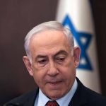 Netanyahu And Trump’s Bilateral Talks On Future Gaza Plans Man in suit with Israeli flag in background.