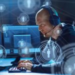 How Funding Cuts Affect Election Cybersecurity Efforts Man with headset working at computer, holographic icons.