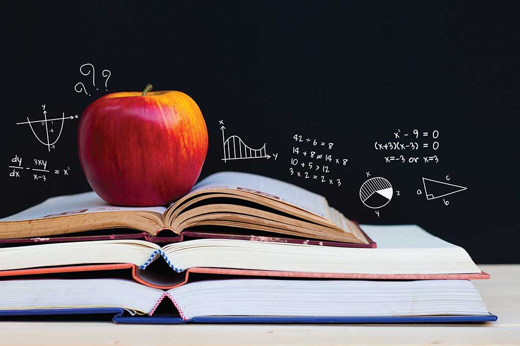 402703882 featured image an apple sits on top of several open books with a chalkboard in the background