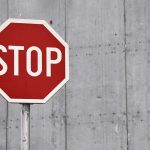 Red States Strategize To Tackle Venezuela’s Tren de Aragua Gang Red stop sign against concrete wall background