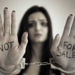 Global Task Force Tackles Complex Human Smuggling Case Handcuffed woman shows "NOT FOR SALE" on her palms.