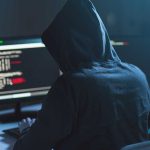 U.S. Transport Systems Are A Hacker’s Goldmine Person in hoodie coding on computer screens.