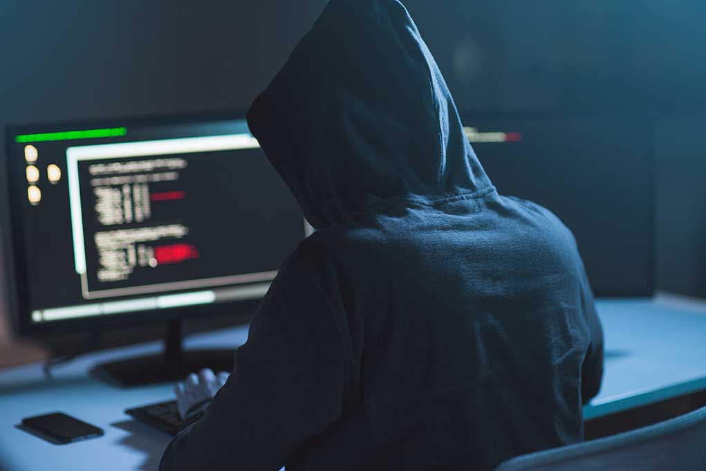 1083511010 featured image Person in hoodie coding on computer screens.