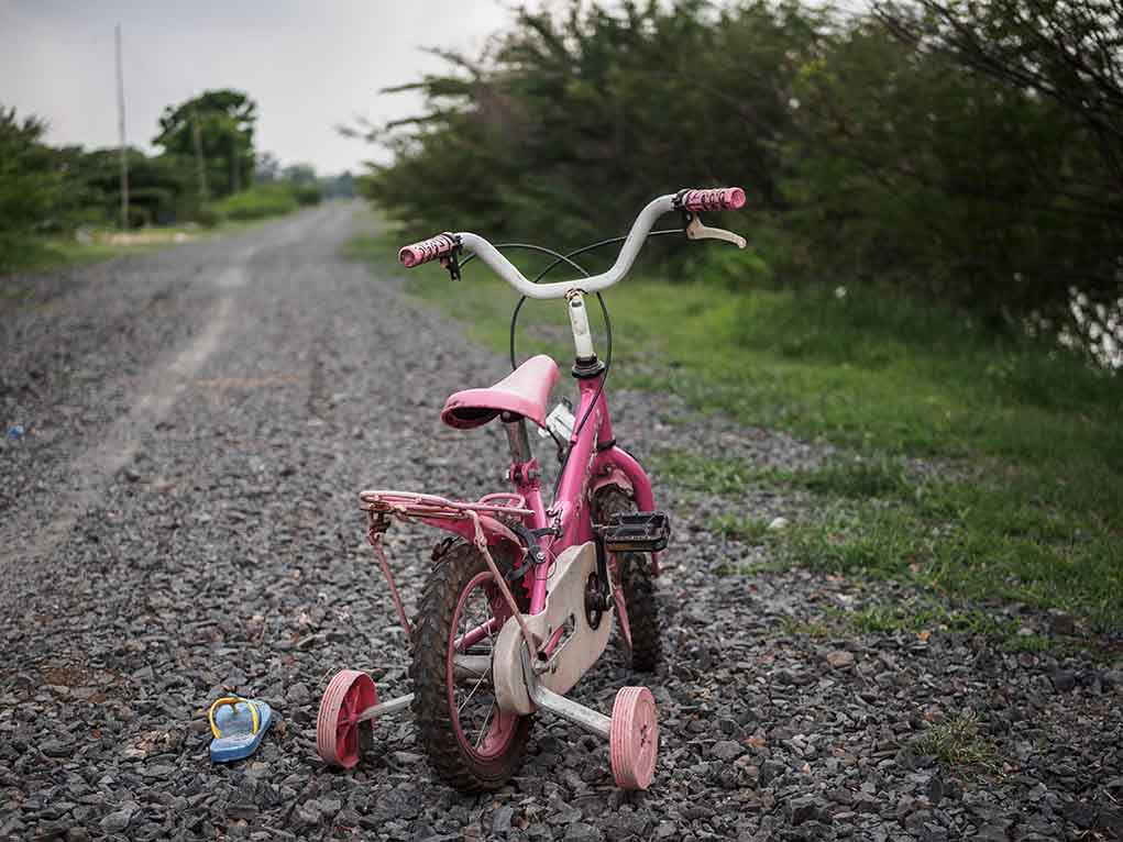 1098020117 featured image Pink children's bike with training wheels on gravel path.