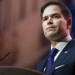 Rubio Defends Administration’s Controversial Immigration Policies Amid Free Speech Issues Man in suit speaking at a podium.