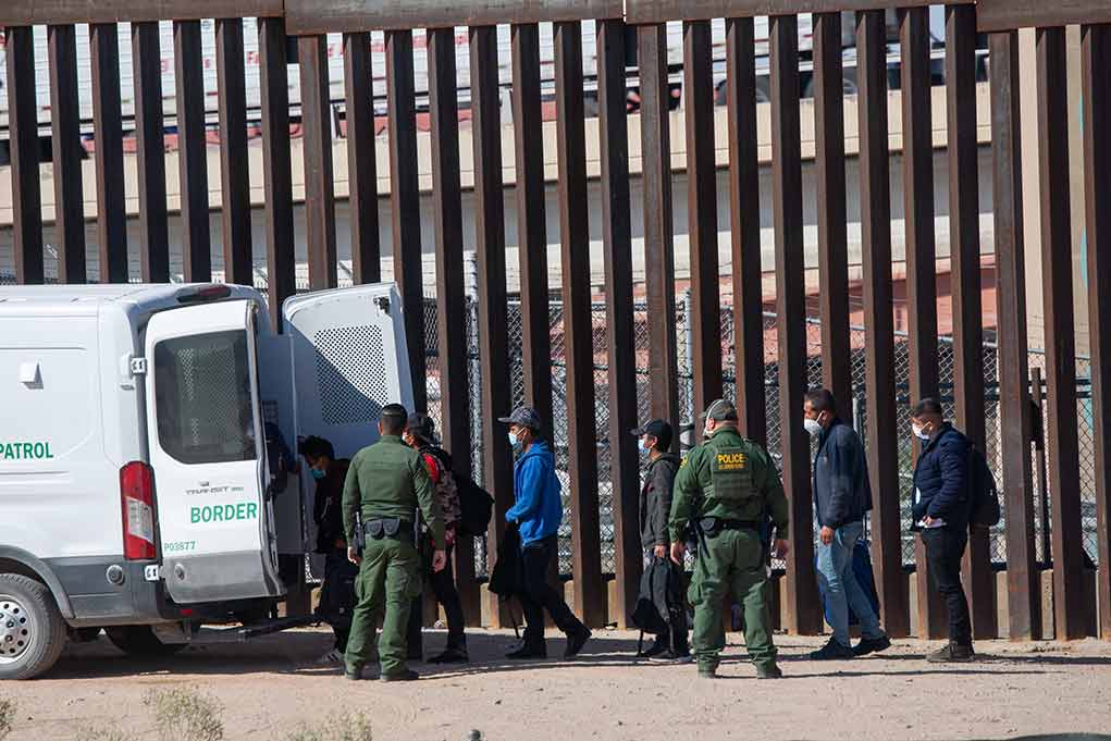 Border patrol agents detaining people near a fence