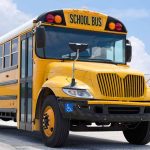 Yellow school bus parked on pavement under blue sky
