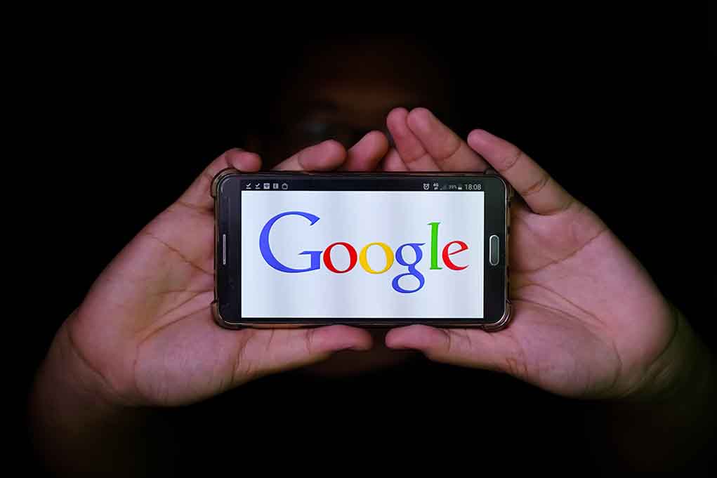 Hands holding smartphone displaying Google logo