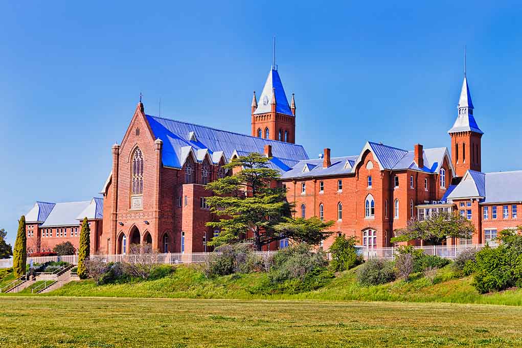 Large red brick building with turrets and green lawn