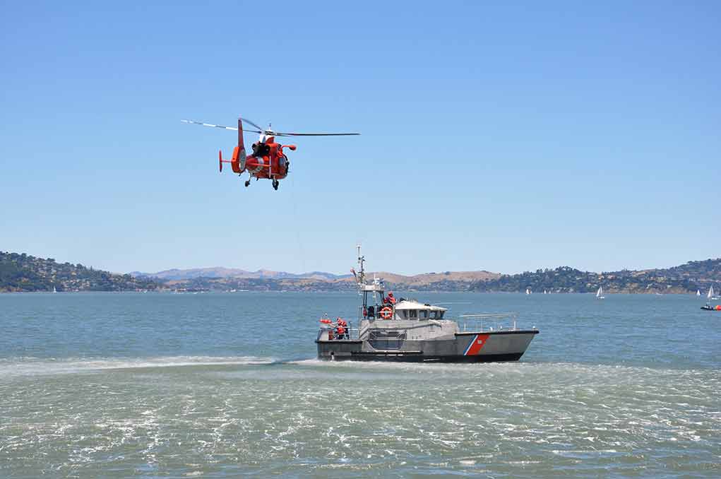 260997440 featured image Helicopter flying above Coast Guard boat on water