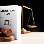 Doctor’s Fight Against State Sparks National Uproar Gavel and abortion law book next to scales