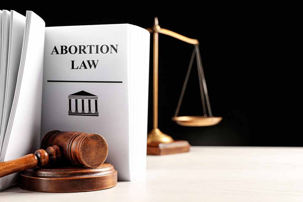 Gavel and abortion law book next to scales