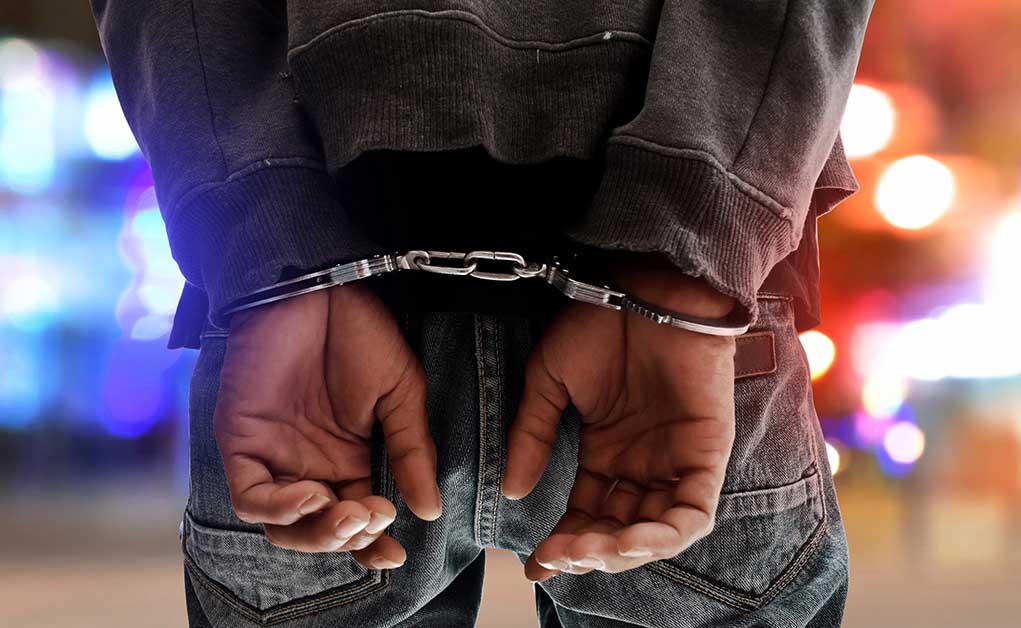 Person in handcuffs with colorful lights in background