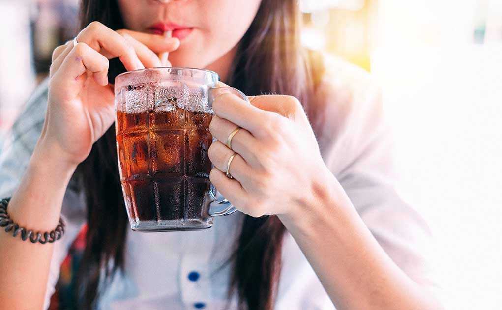 1033381774 Person drinking soda from a glass mug