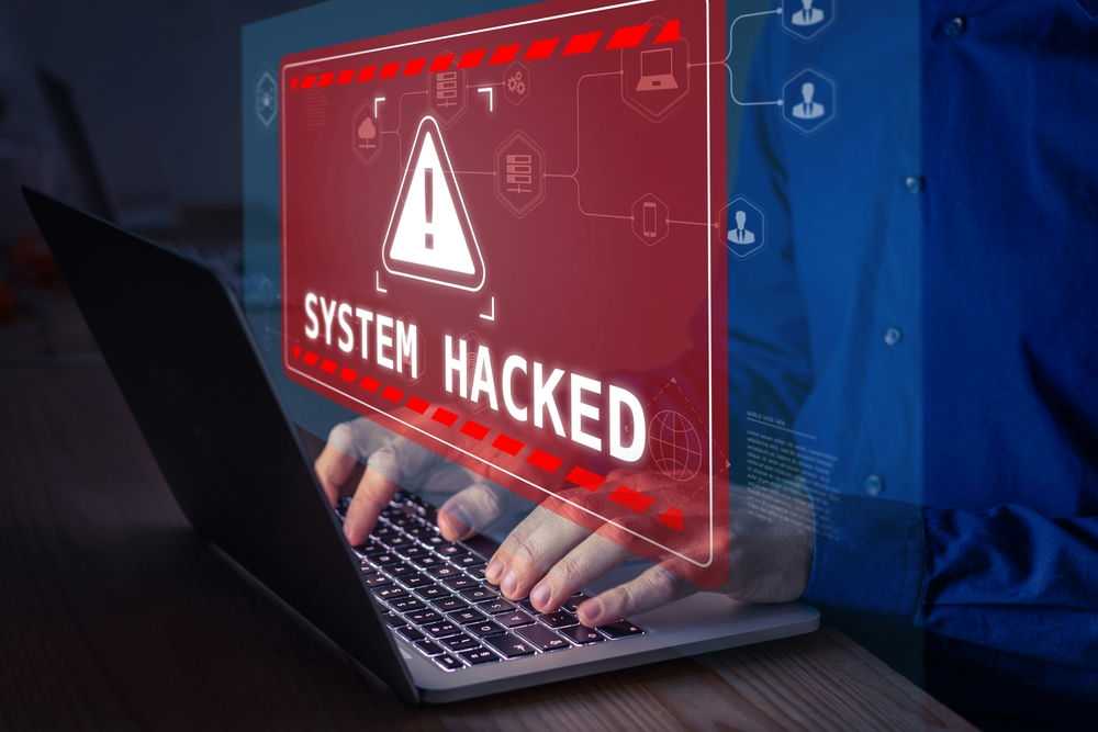 2100631906 Warning sign "System Hacked" on laptop screen.