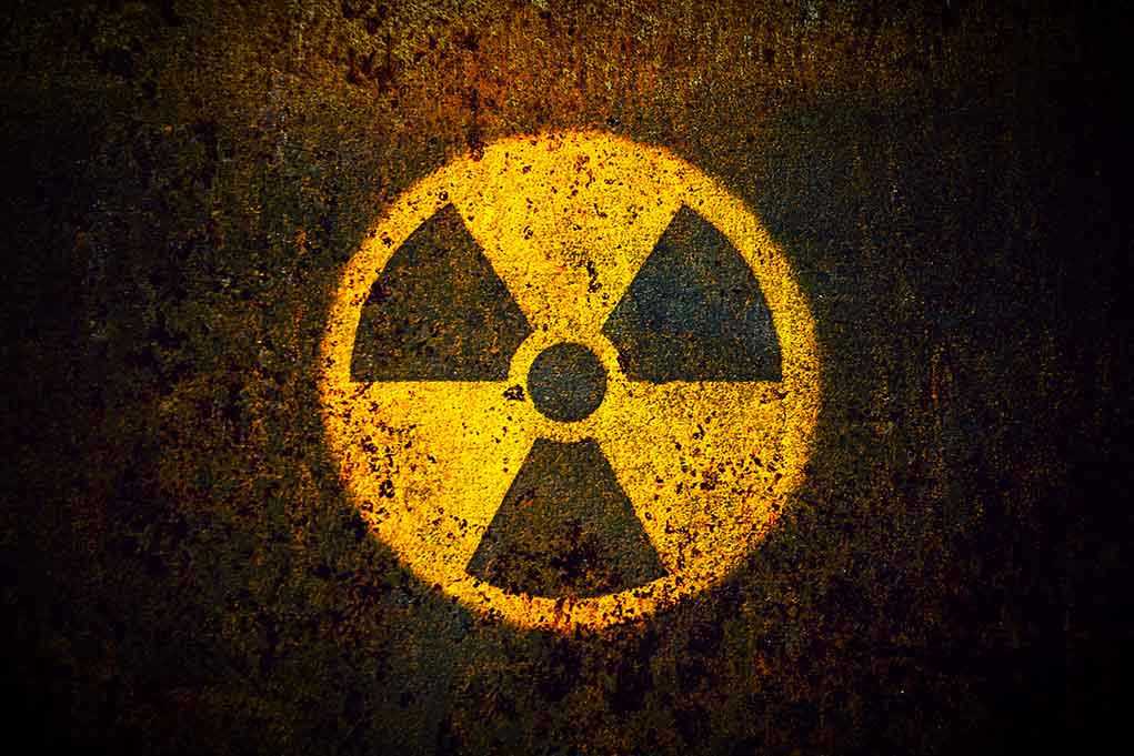 1082372921 Yellow radiation warning symbol on rusty metal surface.