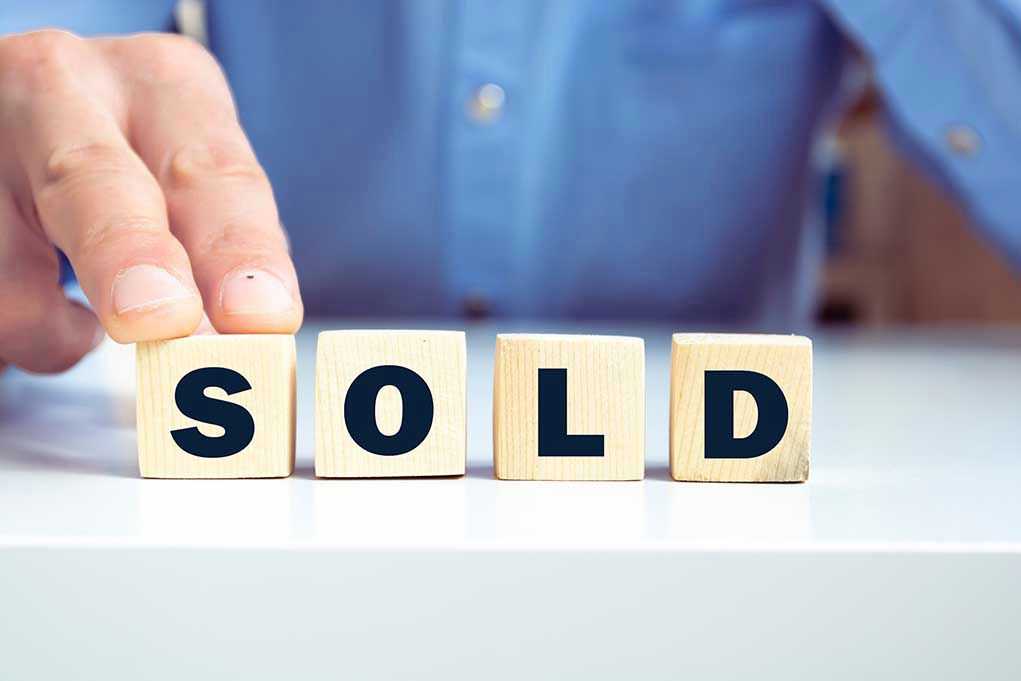 1998726422 Blocks spelling SOLD with a hand touching them.