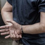 100 Arrests, ZERO Prison Time—How Is He Free? Person in handcuffs with hands behind back.