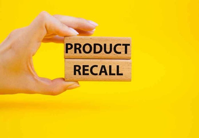 2207157165 Hand holding Product Recall blocks on yellow background.