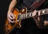 Hands playing an electric guitar.
