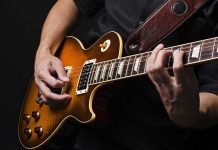 Hands playing an electric guitar.