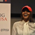 Candace Owens GOES NUTS—Murder Claim STUNS Conservatives A woman wearing a red cap and a white blouse speaking at a political event